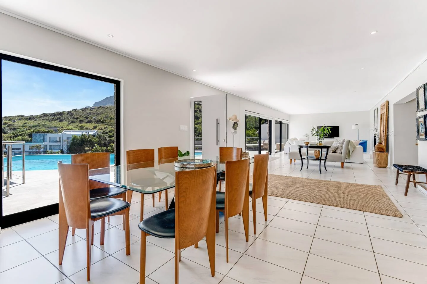 Dining table with lounge and pool visible across the open-plan room