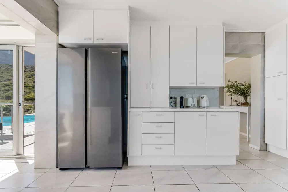 White kitchen with the pool visible through open doors